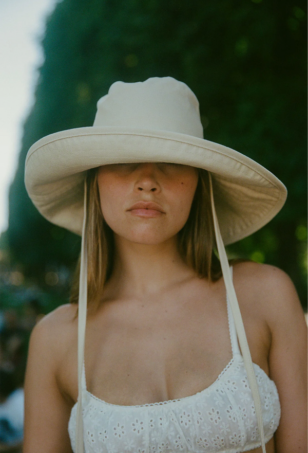 Woman wearing a wide-brimmed beige buckethat with a blurred green background