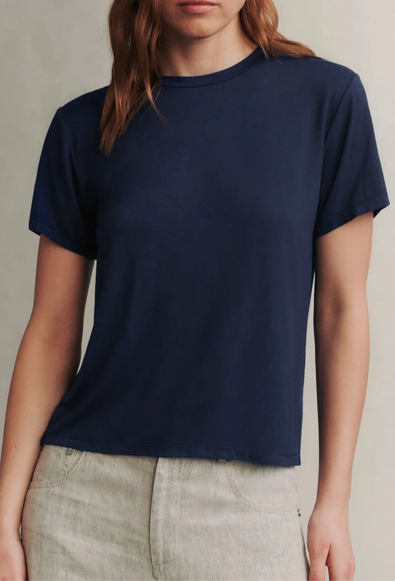 a model wearing a dark blue short sleeve t-shirt and grey pants. white background.