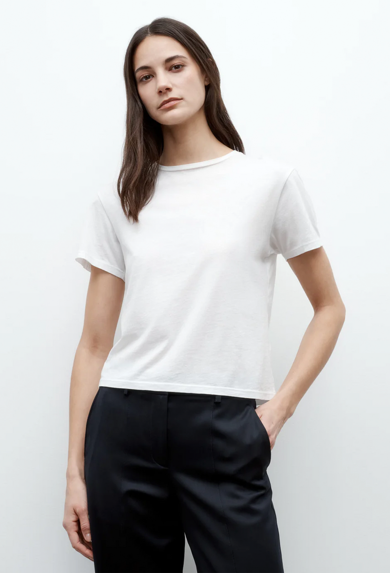 a model wearing a white crewneck tshirt and black pants. white background.