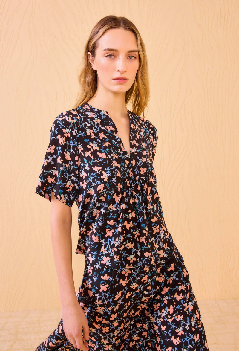 Woman wearing a floral black top against a beige background