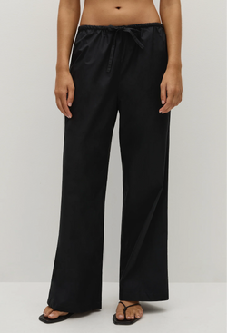 Person wearing black straight-leg pants on a white background