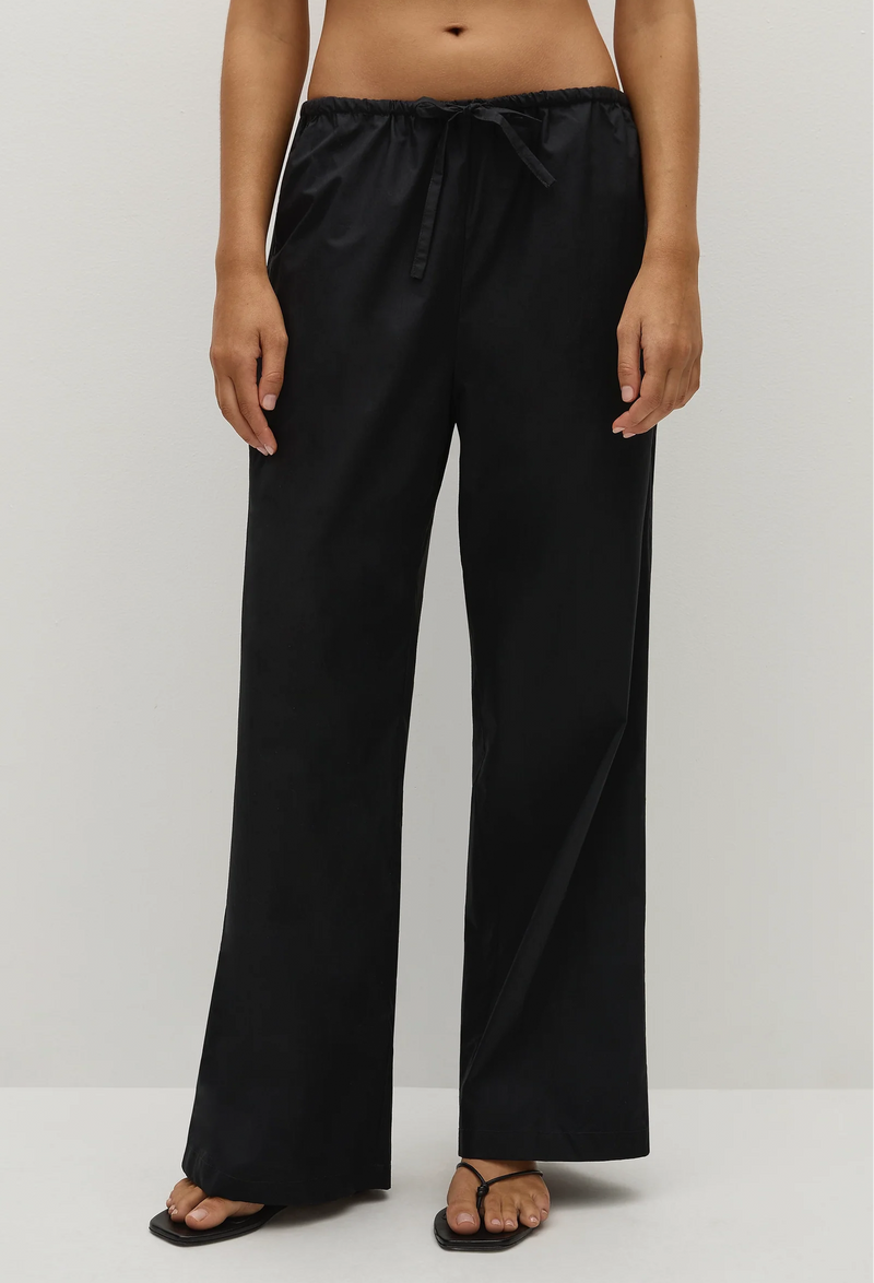 Person wearing black straight-leg pants on a white background