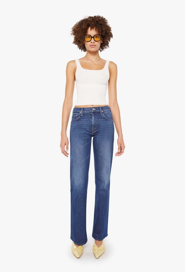 model wearing a white tank top and dark blue jeans on a white background