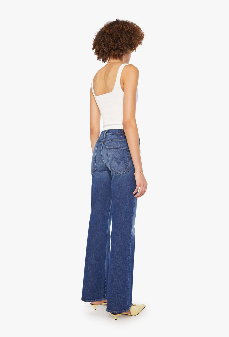 model wearing a white tank top and dark blue jeans on a white background