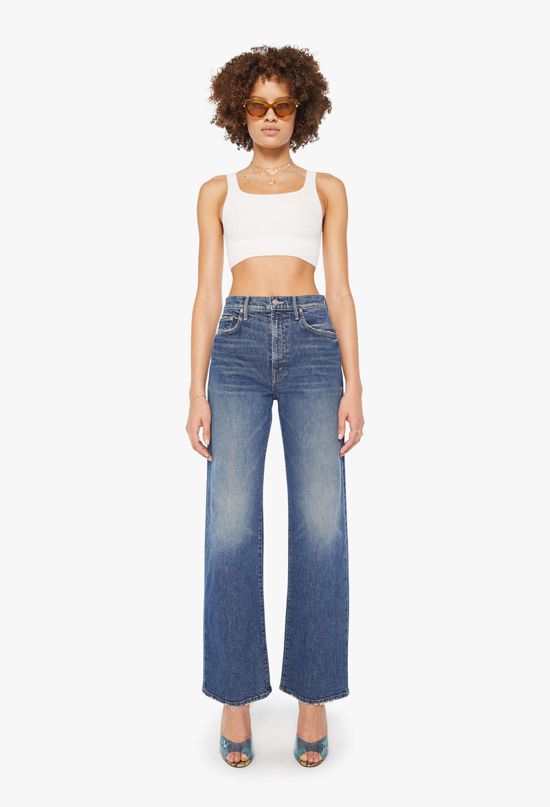 a model wearing wide leg blue jeans on a white background.