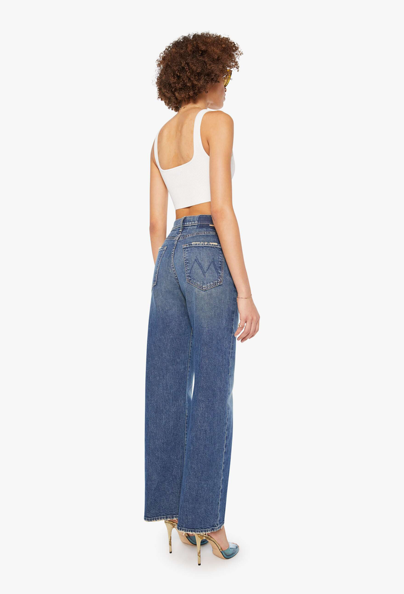a model wearing wide leg blue jeans on a white background.