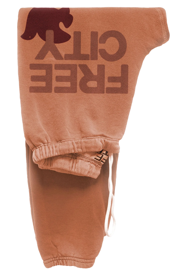 orange sweatpants with 'Free City' text and dove logo on a transparent background