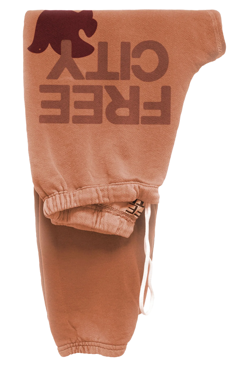 orange sweatpants with 'Free City' text and dove logo on a transparent background