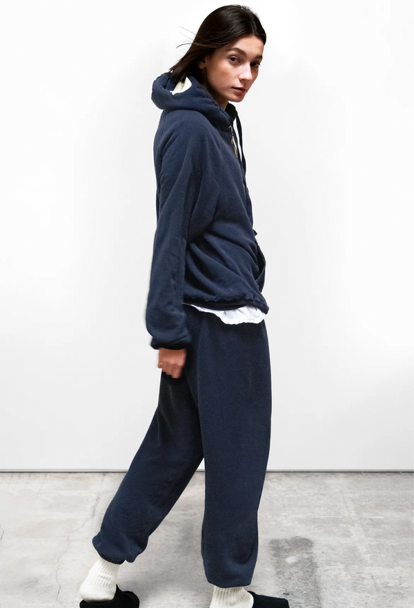 model wearing a navy blue hoodie and pants on a white background