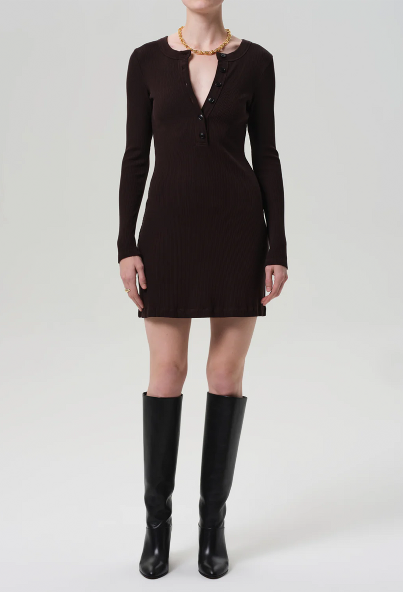Person wearing a dark brown half button down dress with long sleeves and knee-high boots on a white background
