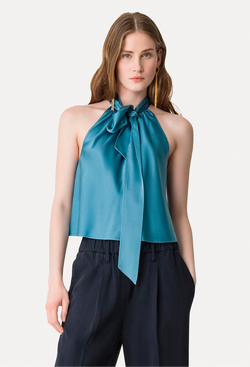 Woman wearing a blue halter top with a large bow neck tie on a white background