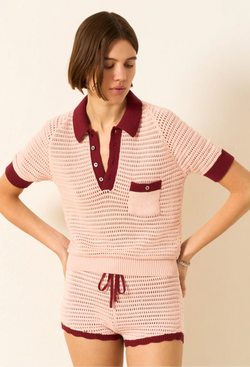 Woman wearing a pink crochet outfit with maroon accents on a beige background