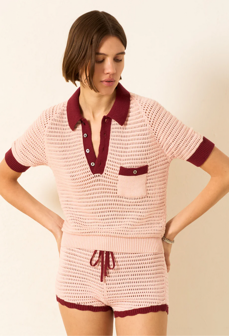 Woman wearing a pink crochet outfit with maroon accents on a beige background