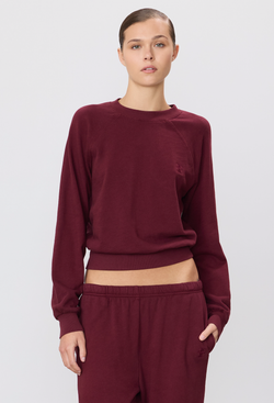 model wearing a burgundy long-sleeve sweatshirt and sweatpants on a white background