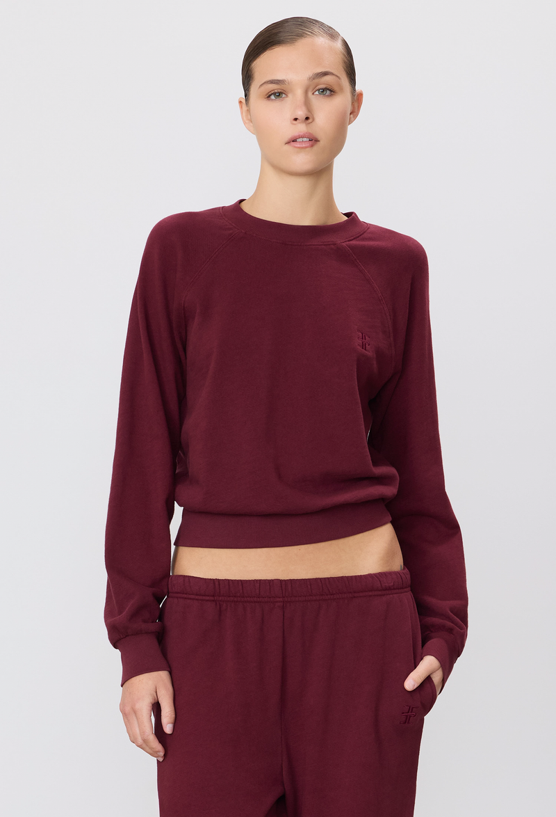 model wearing a burgundy long-sleeve sweatshirt and sweatpants on a white background