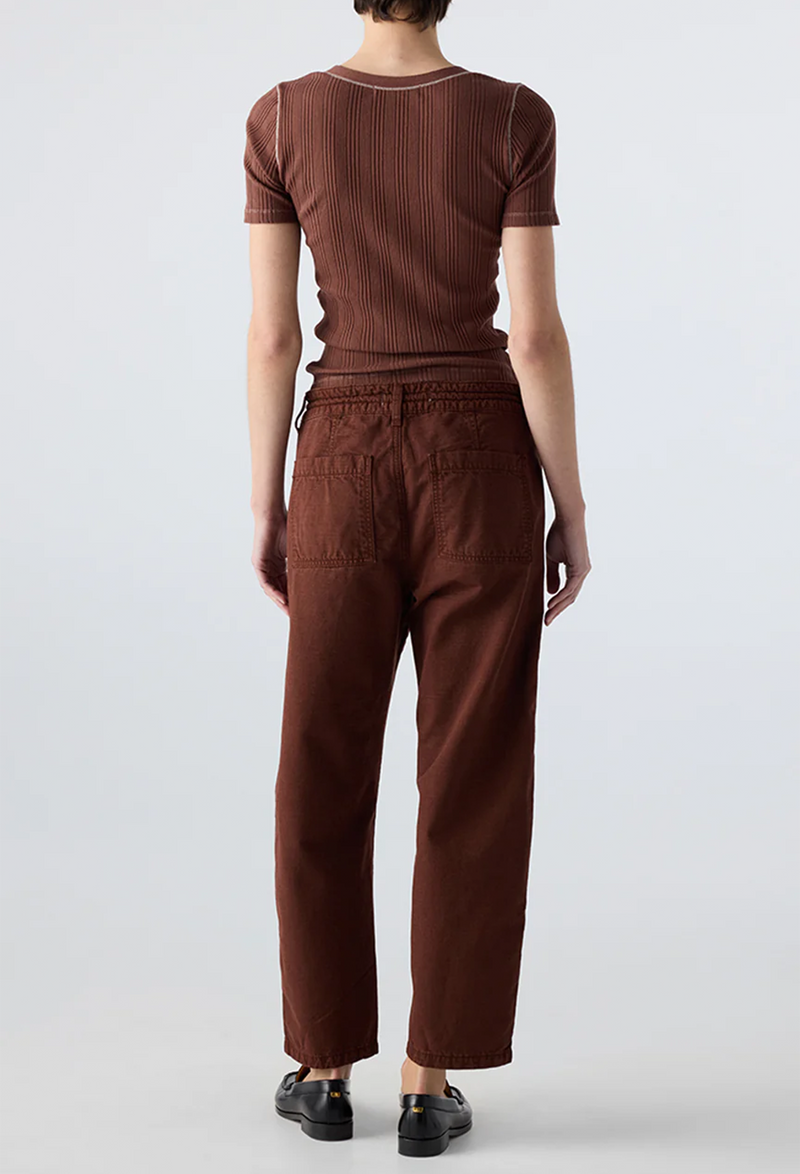 Person wearing a brown ribbed top and brown drawstring pants on a white background
