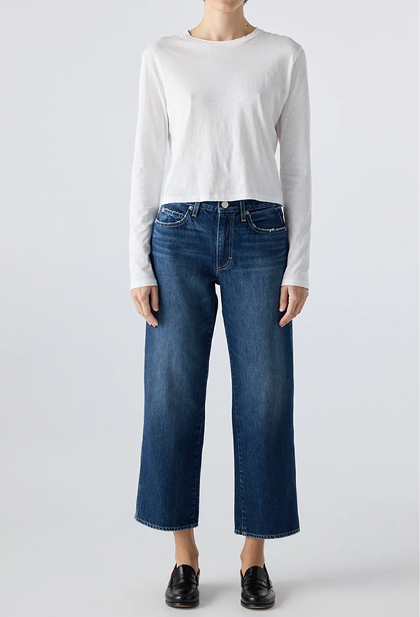 Person wearing a white long-sleeve shirt and blue jeans on a light gray background