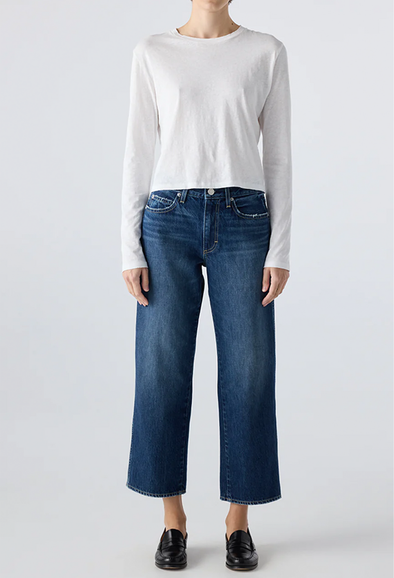 Person wearing a white long-sleeve shirt and blue jeans on a light gray background