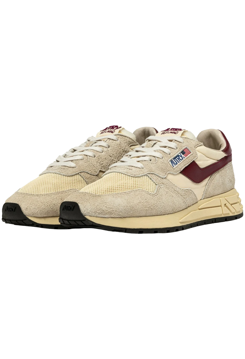 ecru and beige athletic tennis shoes with burgundy accents and black bottoms.