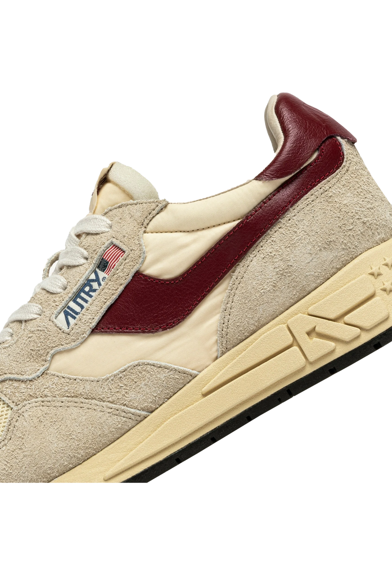 ecru and beige athletic tennis shoes with burgundy accents and black bottoms.