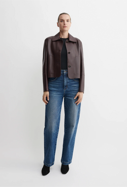 Person wearing a red/brown leather jacket and blue jeans on a white background