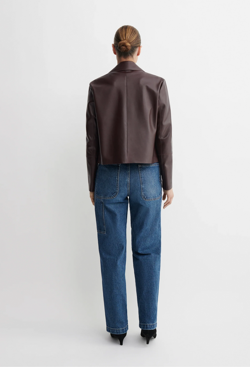 Person wearing a red/brown jacket and blue jeans on a white background