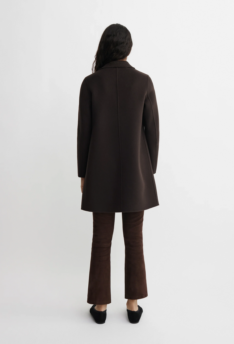 Person wearing a brown coat and pants on a white background