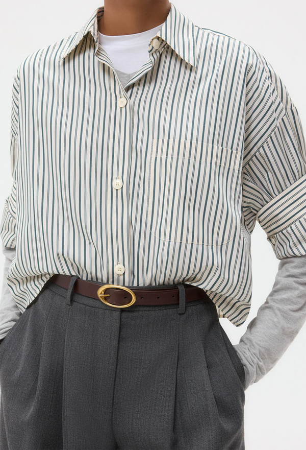 Person wearing a white shirt with green stripes and gray pants with a white background