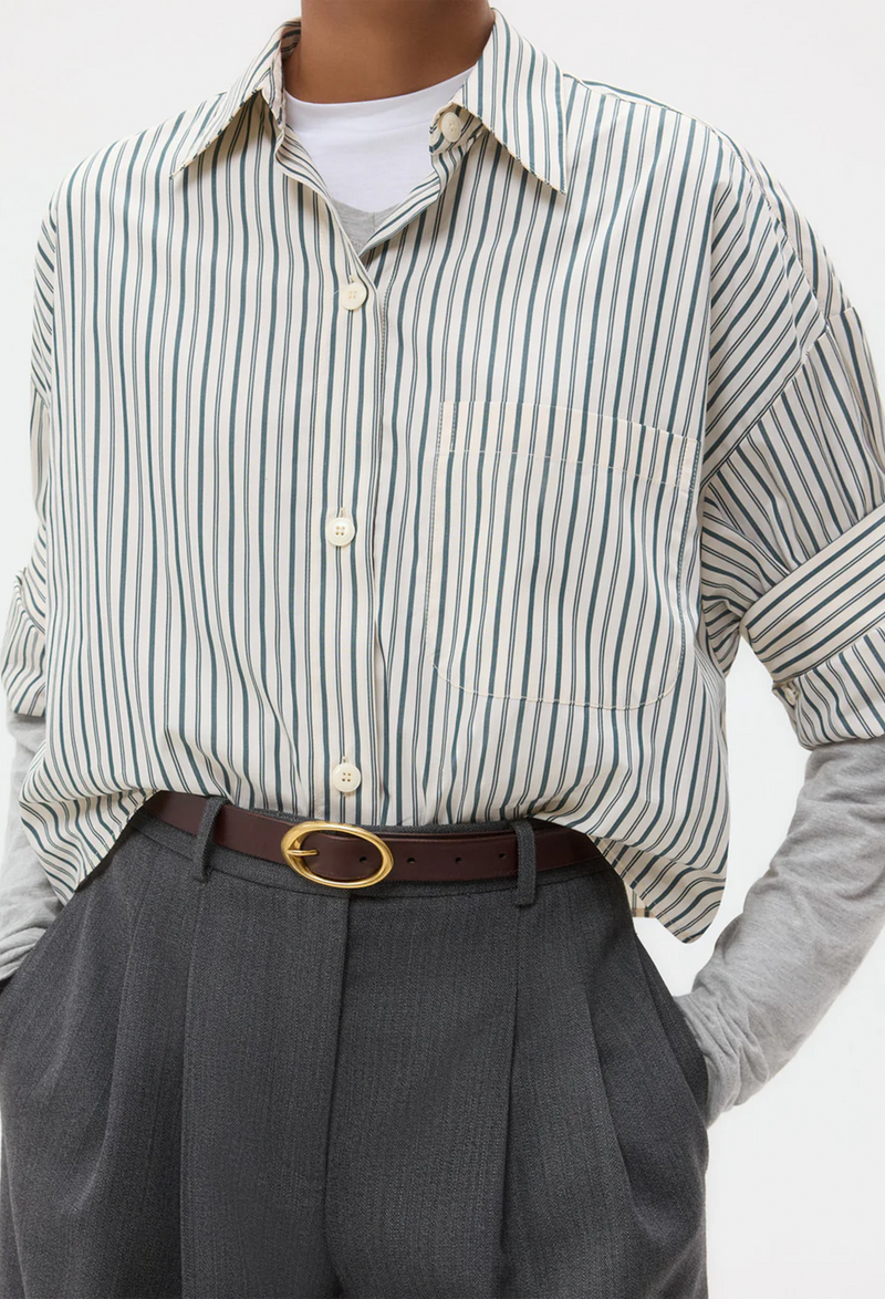 Person wearing a white shirt with green stripes and gray pants with a white background