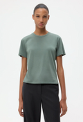 Person wearing a green t-shirt and black pants on a white background