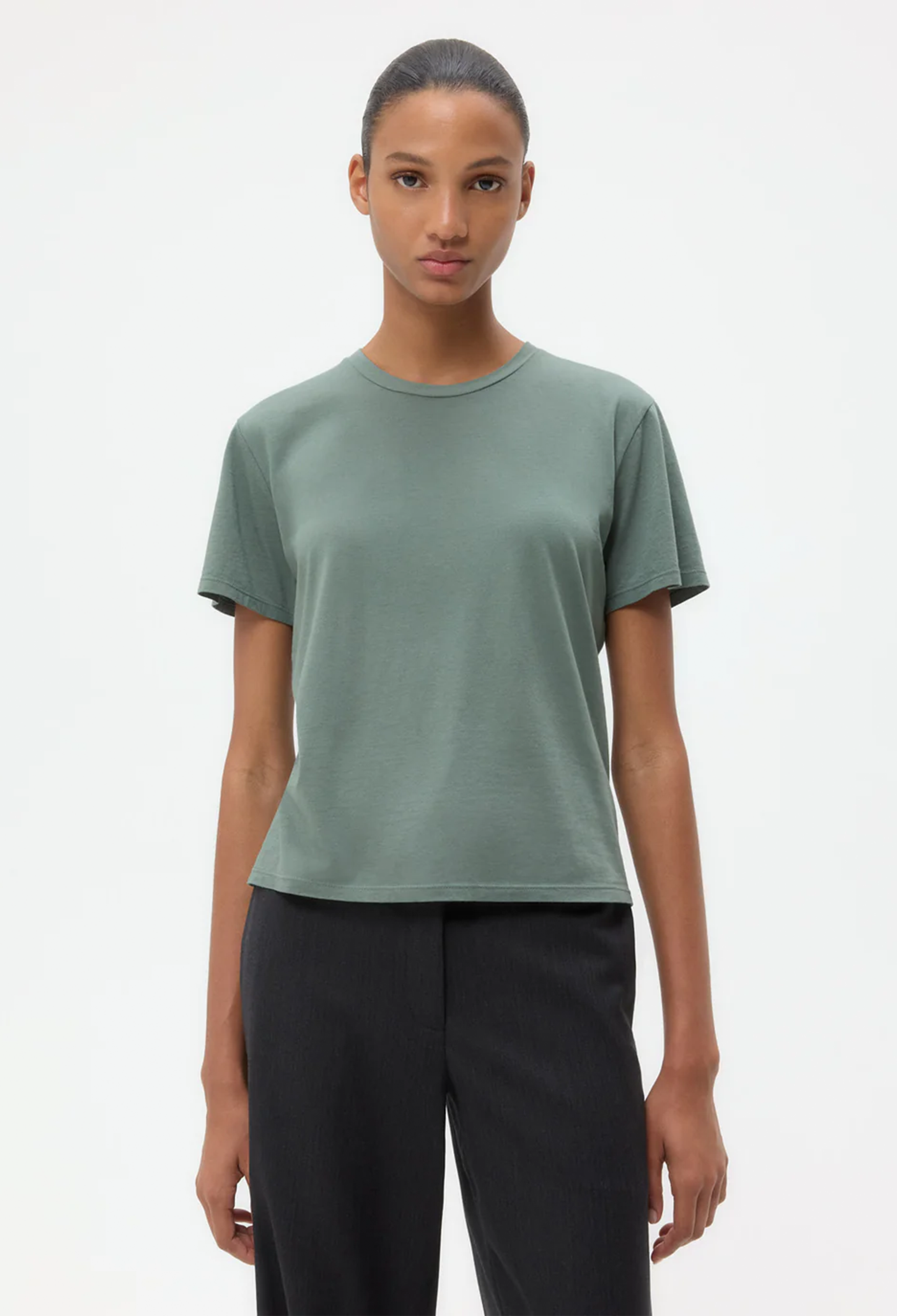 Person wearing a green t-shirt and black pants on a white background