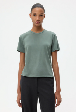 Person wearing a green t-shirt and black pants on a white background
