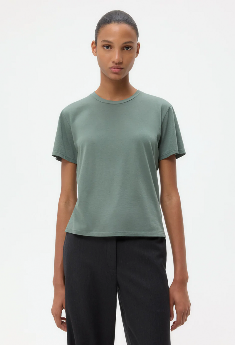 Person wearing a green t-shirt and black pants on a white background