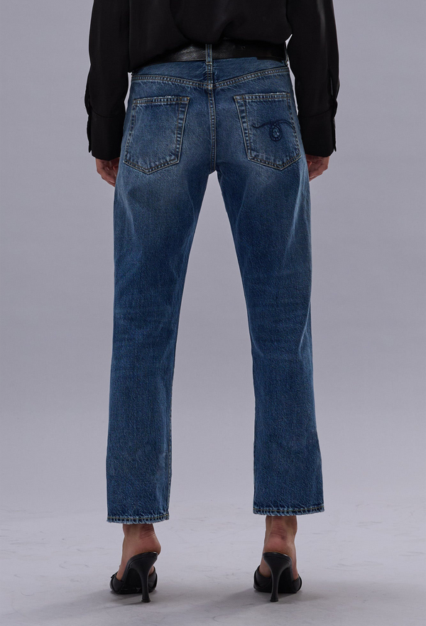 Person wearing blue jeans from behind on a gray background