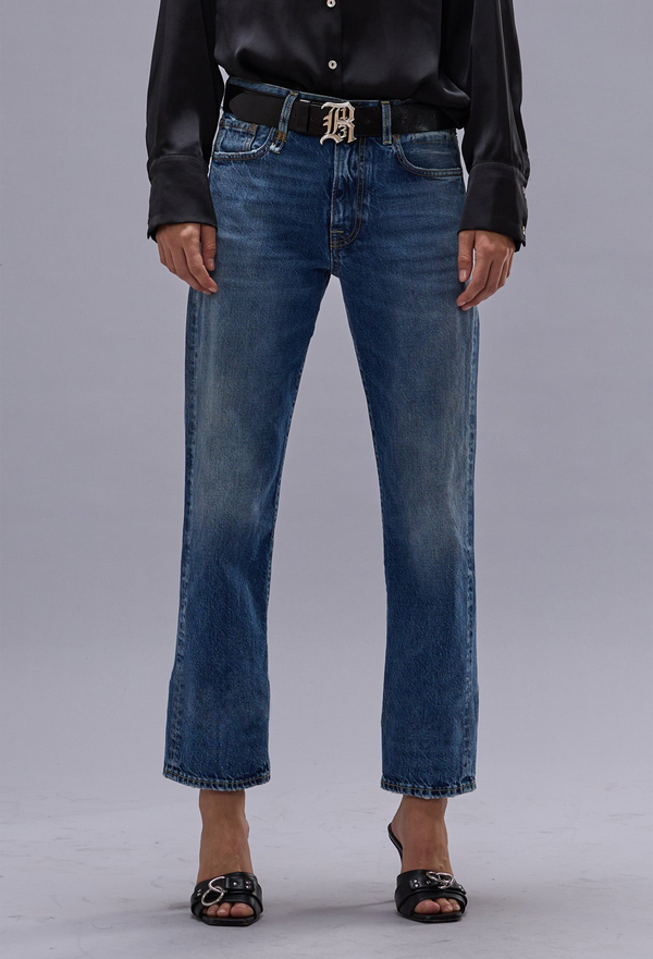 Person wearing blue jeans and a black leather jacket on a gray background