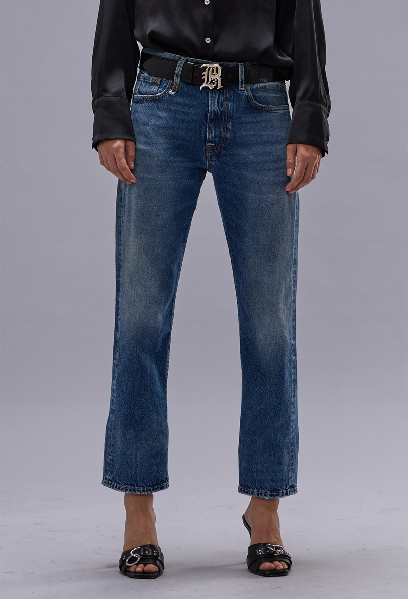Person wearing blue jeans and a black leather jacket on a gray background