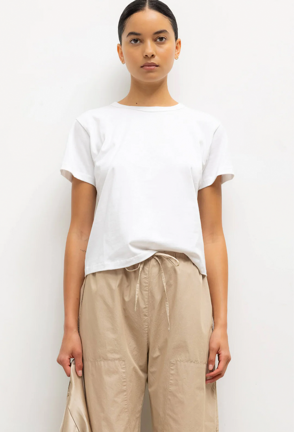 Person wearing a white t-shirt and beige pants against a plain background