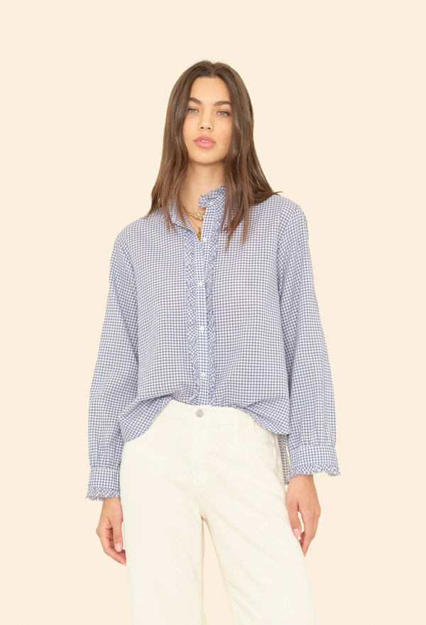 Woman wearing a blue checkered long sleeve button down shirt against a beige background