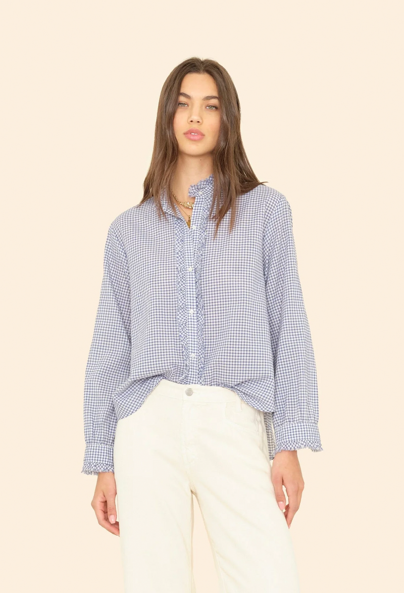 Woman wearing a blue checkered long sleeve button down shirt against a beige background