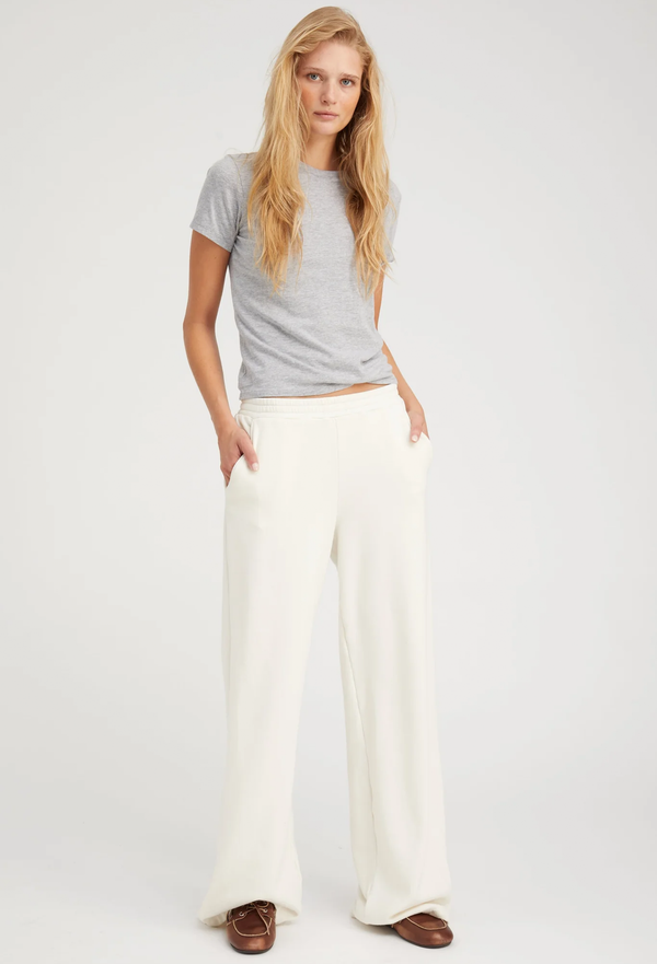 Woman wearing a gray t-shirt and white wide-leg pants on a white background