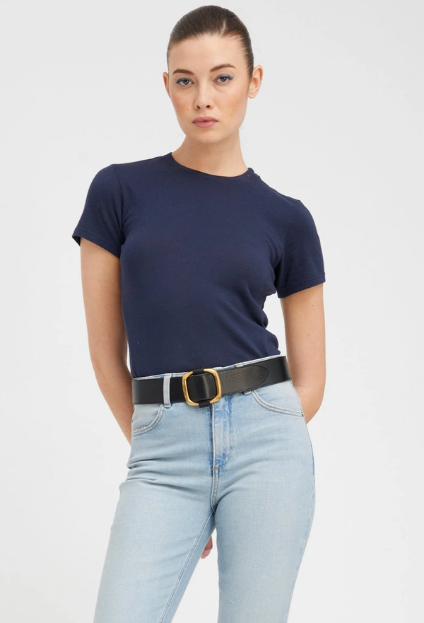 Person wearing a navy t-shirt and light blue jeans with a belt on a white background