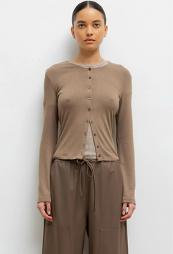Woman wearing a light brown long-sleeve cardigan and pants on a white background