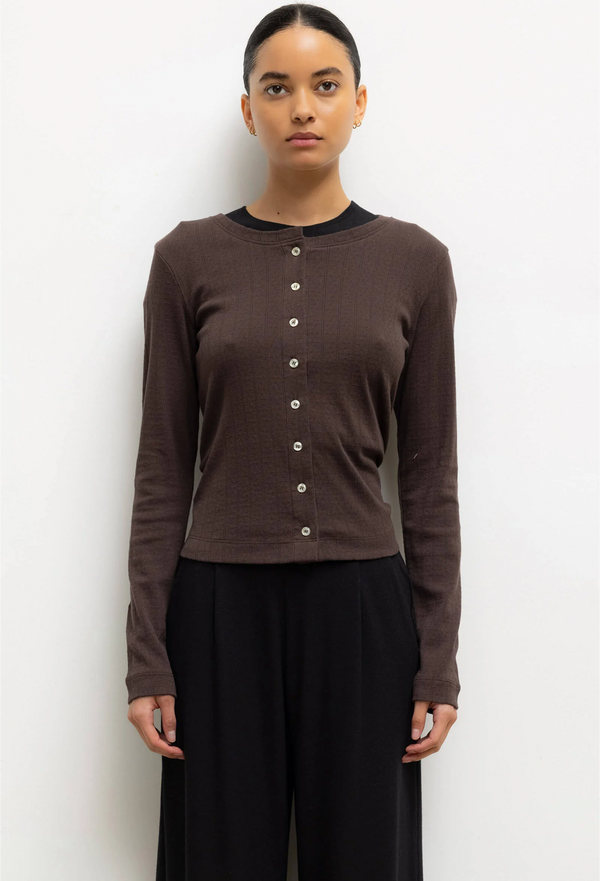 Woman wearing a brown cardigan with buttons against a white background