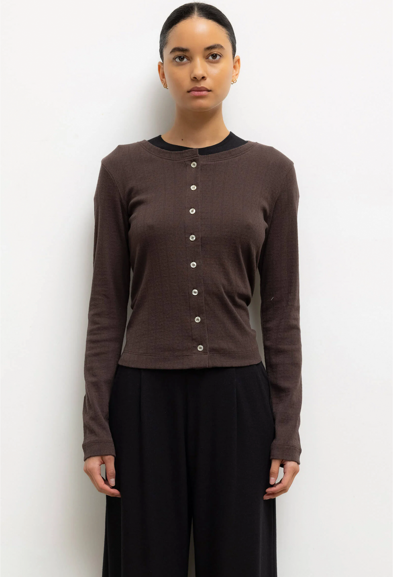 Woman wearing a brown cardigan with buttons against a white background