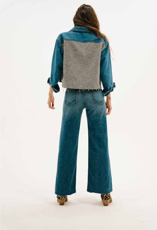 Person wearing a denim jacket and jeans against a white background.