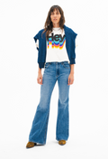 Person wearing a blue cardigan, white t-shirt with colorful text, and blue jeans on a white background