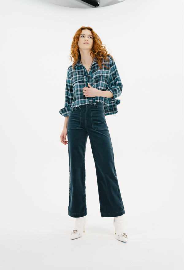 Woman wearing a blue plaid flannel and dark jeans on a white background