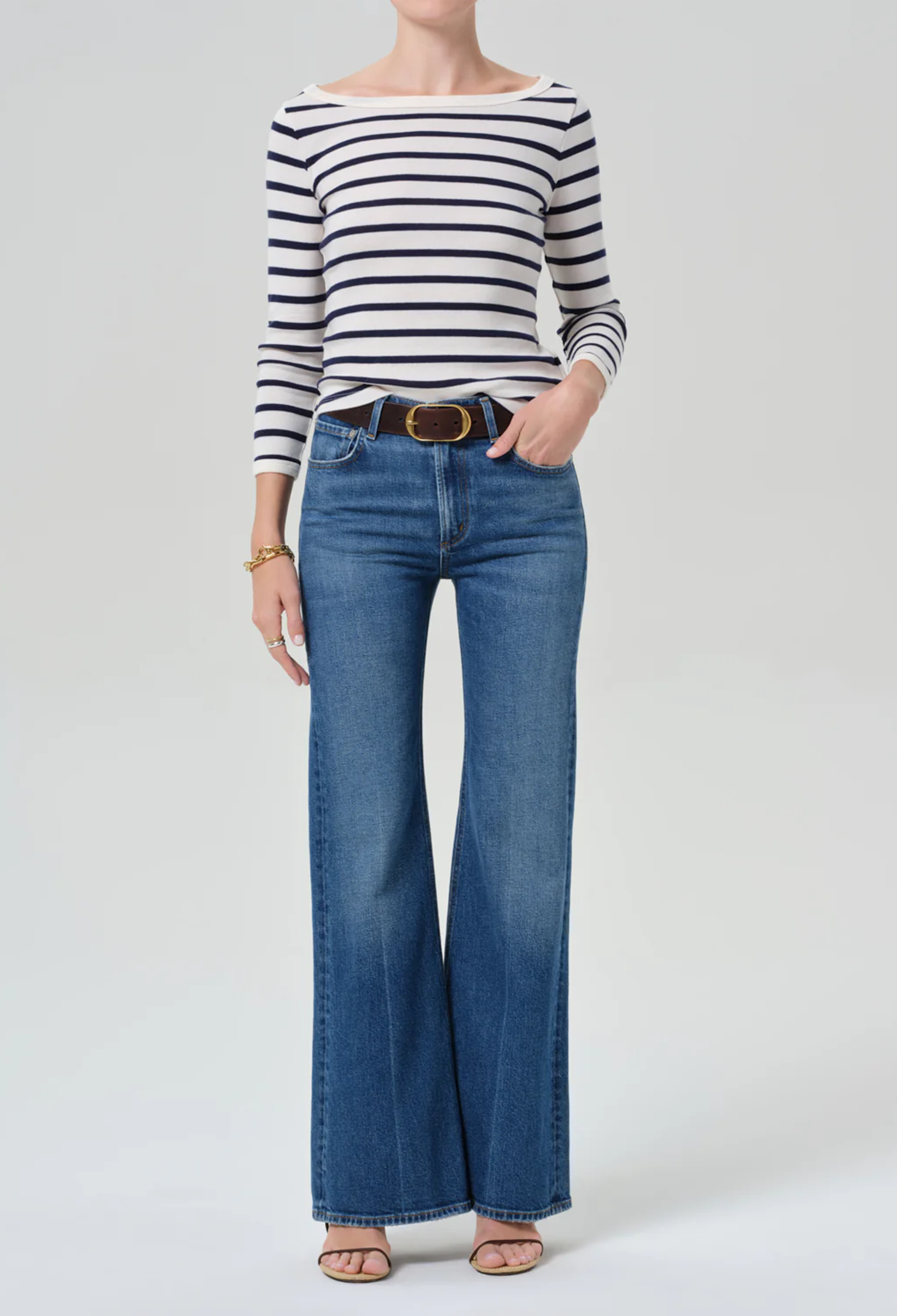 Person wearing a striped shirt and blue jeans on a white background