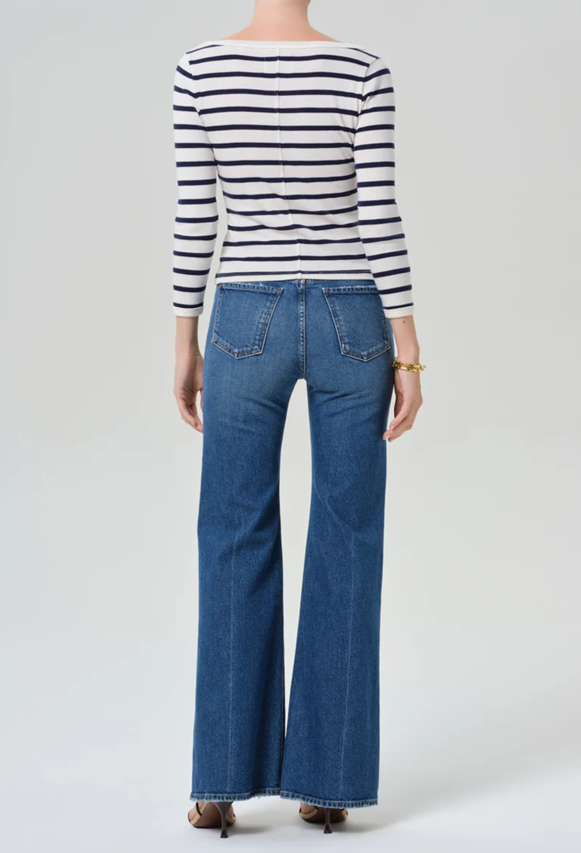 Person wearing a striped shirt and blue jeans on a white background