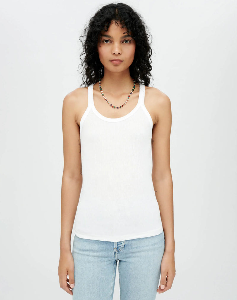 MODEL WEARING THE RE/DONE RIBBED TANK TOP WITH A MULTICOLORED BEADED NECKLACE AND LIGHT WASH JEANS. MODEL IS UP AGAINST A LIGHT GREY BACKGROUND